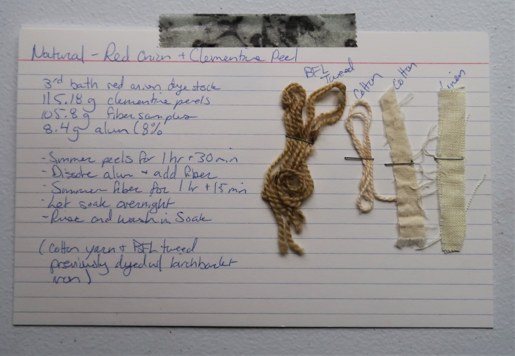 An index card on a white table. On the left, the information for the red onion and clementine peel dye detailed on this web page is handwritten in blue ink. 

On the right,2 yarn samples and 2 fabric samples are stapled. The BFL Tweed is a light brown. The cotton yarn, cotton fabric, and linen fabric samples are a light tan. The linen sample is little more yellow than the others.