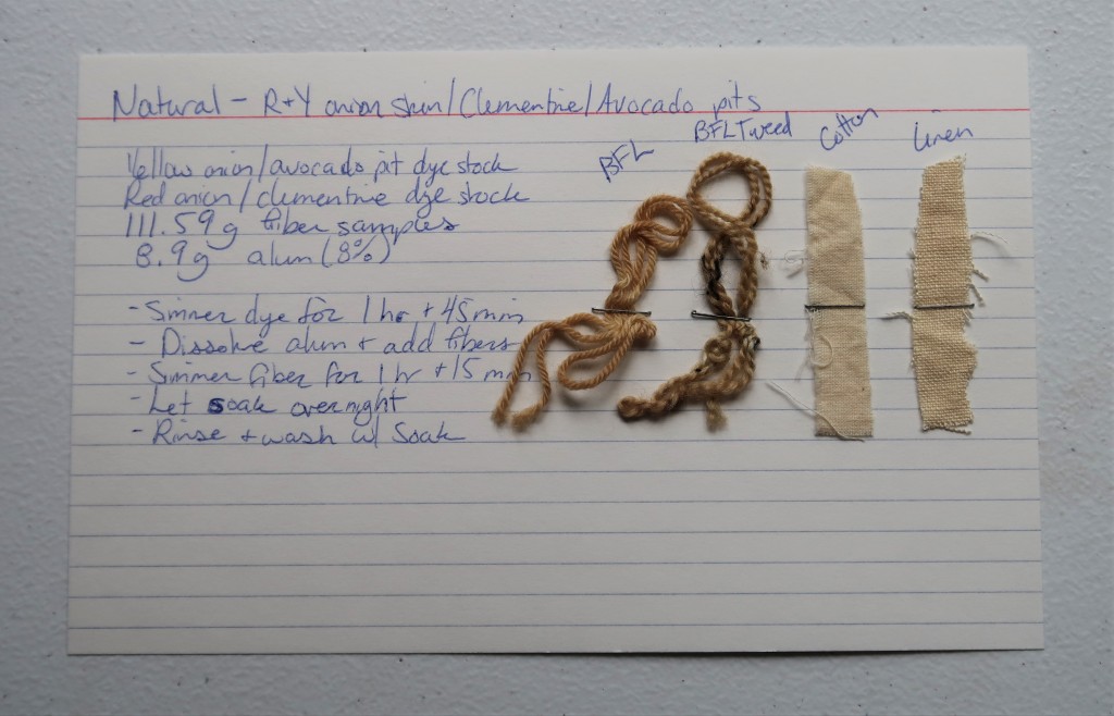 An index card on a white table. On the left, the information for the combination dye detailed on this web page is handwritten in blue ink. 

On the right are stapled two yarn samples and 2 fabric samples. The two yarn samples are a golden tan, but the BFL tweed is darker than the other. The cotton and linen fabric samples are a light tan.
